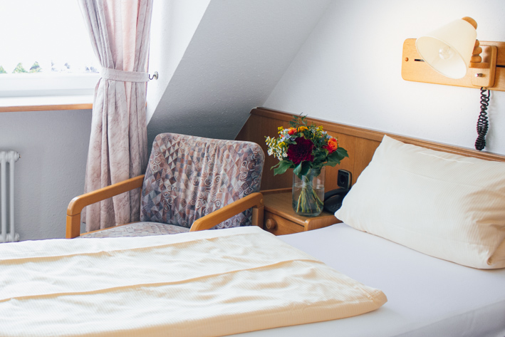 Komfortables Einzelzimmer mit gemütlichem Bett und bequemen Sessel – ideal für Alleinreisende im Hotel.